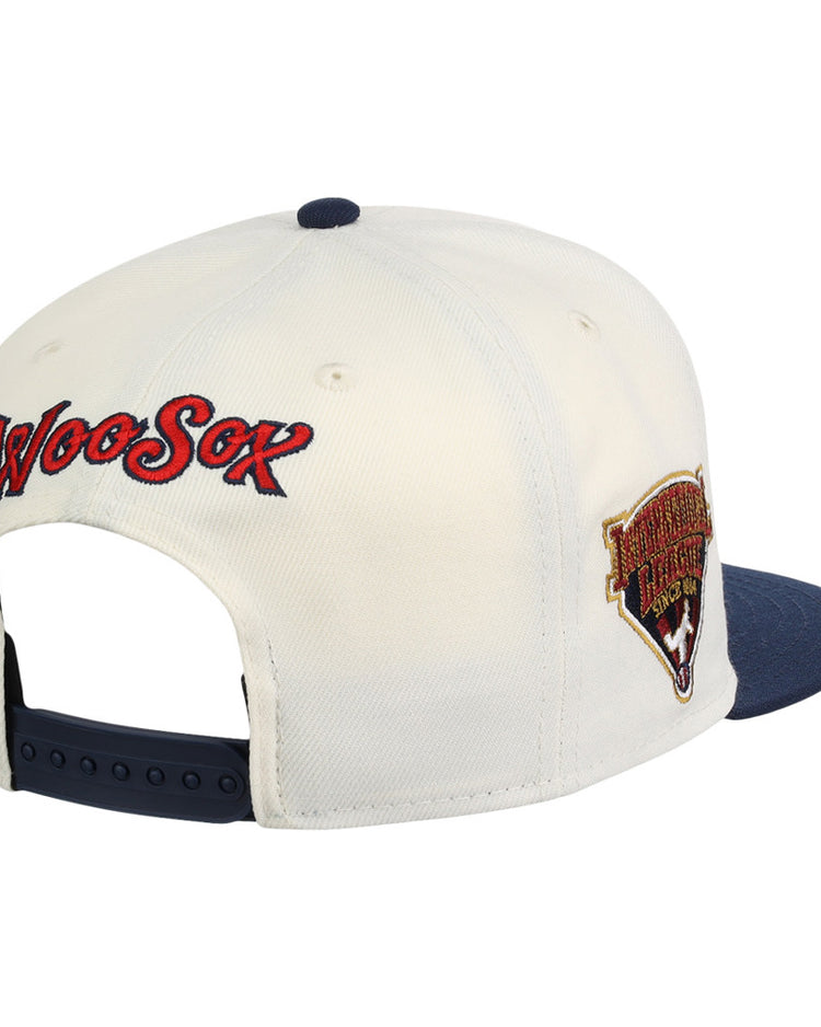 The Ebbets Field Worcester Red Sox MiLB Snapback Ballcap features a cream crown, navy brim, adjustable strap, WooSox embroidered in red and blue on the back, and a team logo patch on the side.