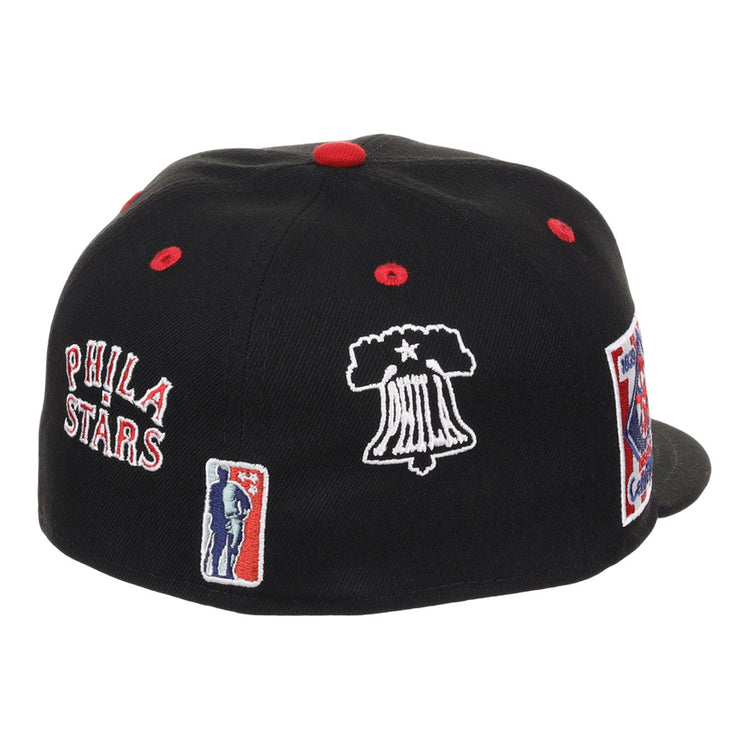 The Ebbets Field Philadelphia Stars NLB Varsity Fitted Ballcap is black with red and white embroidered PHILA STARS, a Liberty Bell, and a basketball player. Red accents highlight the button and ventilation holes.