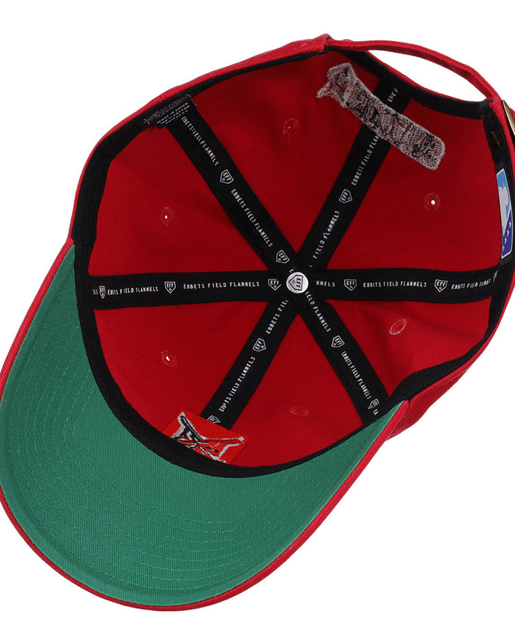 The image shows the inside of the Indianapolis Indians MiLB Dad Ballcap by Ebbets Field, featuring a red exterior, green underbill, black interior taping with white text, adjustable back strap, and visible inner seams and stitching.