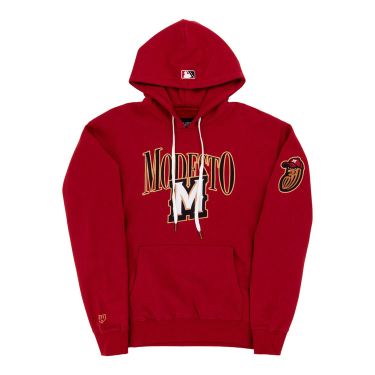 The Ebbets Field Modesto Nuts MiLB Cotton Hooded Sweatshirt is a red hoodie with MODESTO and a large gold and white M on the front, a red bird head patch on the left sleeve, and an MLB logo on the hood.