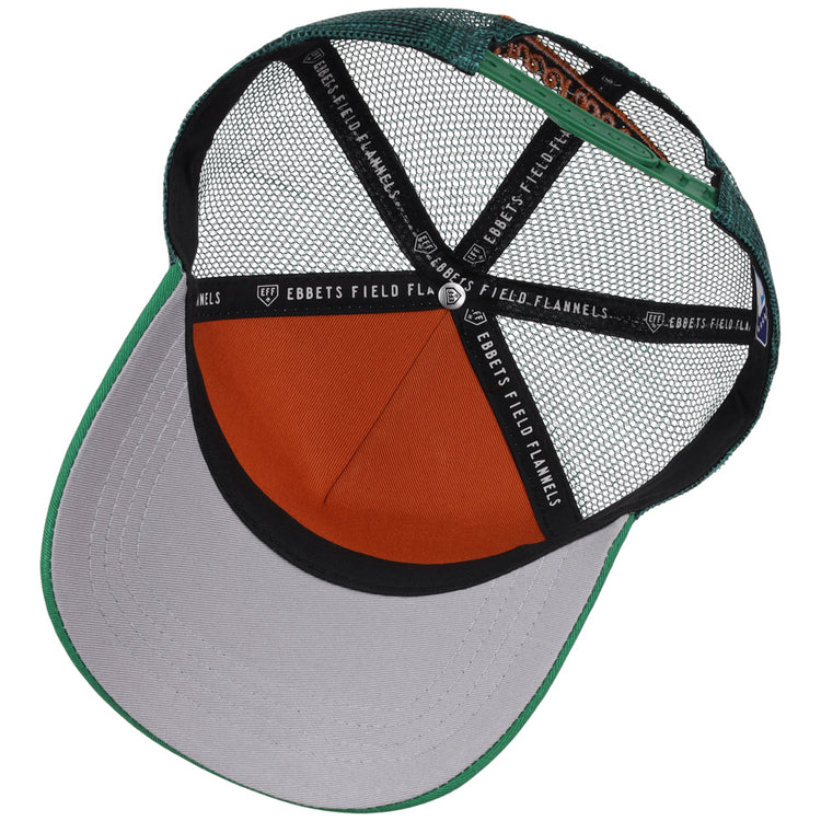 The inside view of the Greensboro Grasshoppers MiLB Trucker Ballcap by Ebbets Field shows green, gray, and orange mesh panels, an orange sweatband, and black straps labeled “EBBETS FIELD FLANNELS.”.