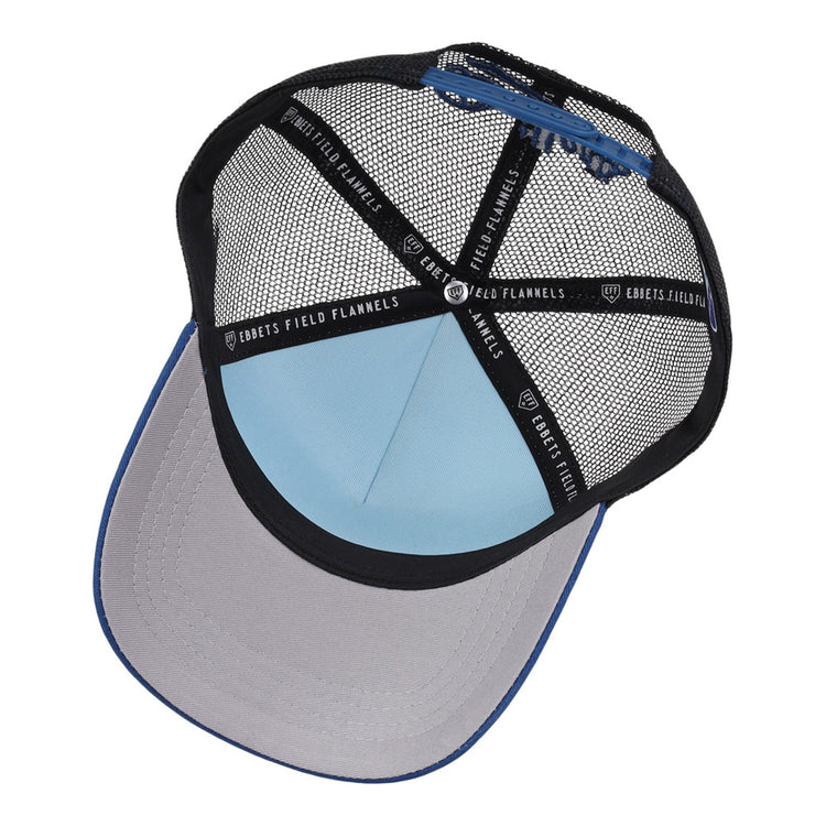 A top-down view of the Tulsa Drillers MiLB Trucker Ballcap by Ebbets Field shows its light blue crown, grey under-brim, black mesh panels, and interior branded black tape reading Ebbets Field Flannels.