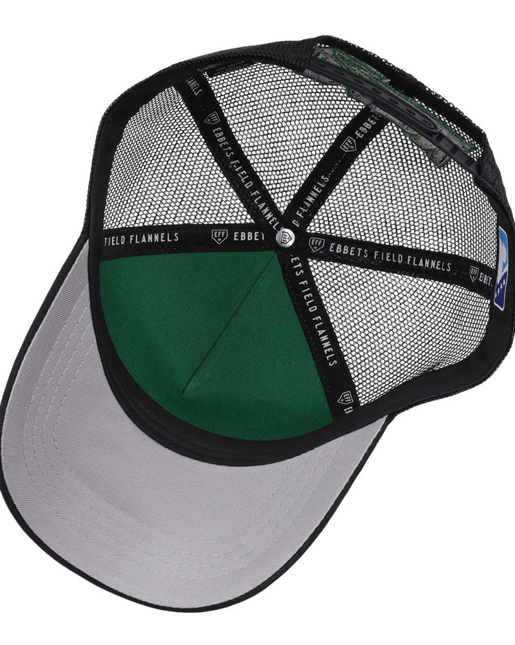 A top-down view of the inside of the black Dayton Dragons MiLB Trucker Ballcap by Ebbets Field, featuring a gray brim, green interior panel, and inner bands with 