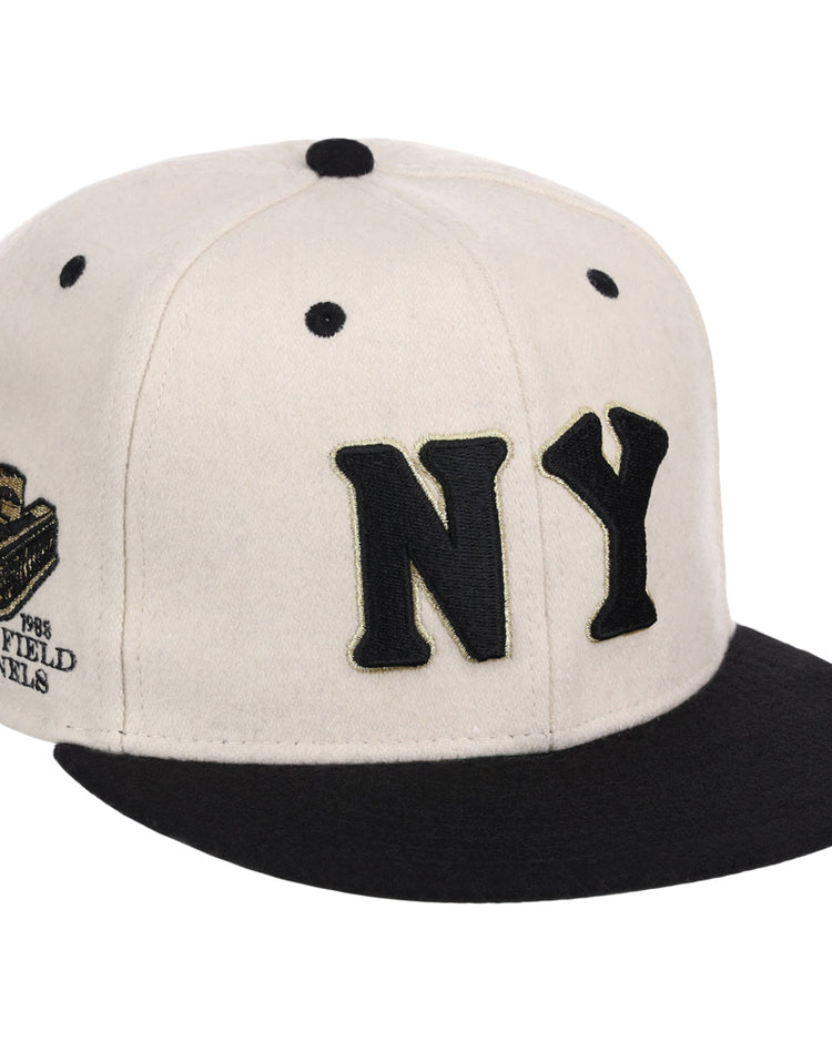 The Ebbets Field New York Black Yankees NLB Ballpark Fitted Ballcap is cream with a black brim, large black NY letters on the front, and an embroidered patch with text and logo on the side.