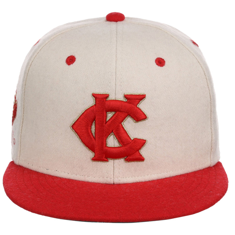 The Ebbets Field Kansas City Monarchs NLB Ballpark Fitted Ballcap is cream-colored with a red brim, red embroidered KC logo on the front, and features red accents on the top button and ventilation holes.