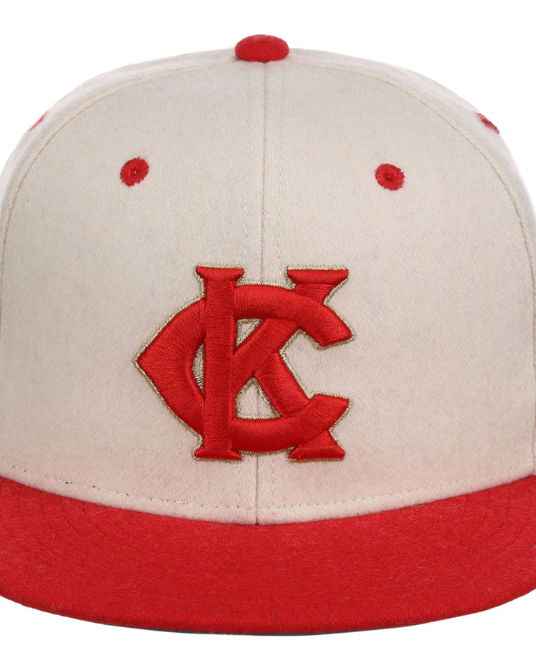 The Ebbets Field Kansas City Monarchs NLB Ballpark Fitted Ballcap is cream-colored with a red brim, red embroidered KC logo on the front, and features red accents on the top button and ventilation holes.