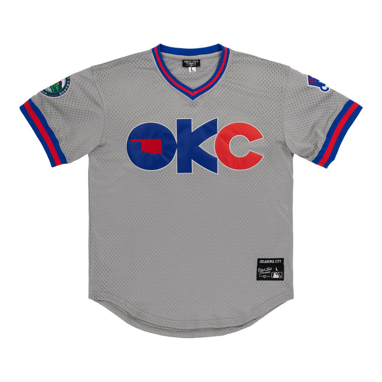 The Ebbets Field Oklahoma City 89Ers MiLB V-Neck Jersey features gray mesh with blue and red trim, OKC in bold on the front with an Oklahoma state silhouette inside the O, sleeve patches, and a stitched label near the hem.