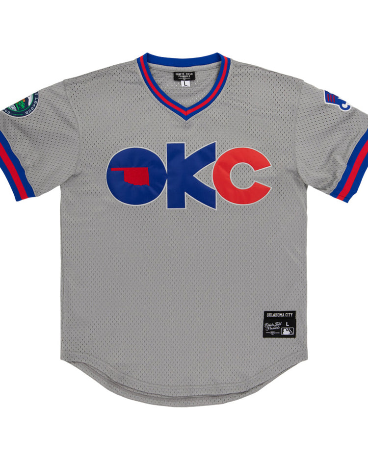 The Ebbets Field Oklahoma City 89Ers MiLB V-Neck Jersey features gray mesh with blue and red trim, OKC in bold on the front with an Oklahoma state silhouette inside the O, sleeve patches, and a stitched label near the hem.