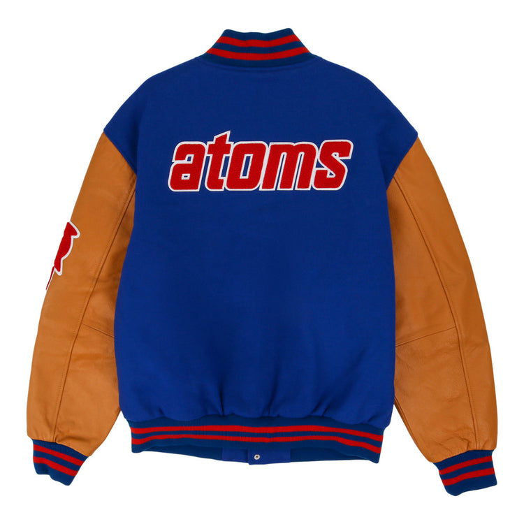 The Sankei Atoms Dna Varsity Jacket by Ebbets Field features blue fabric, tan leather sleeves, red-and-blue striped cuffs, and 