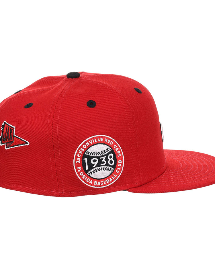 The Ebbets Field Jacksonville Red Caps NLB Varsity Fitted Ballcap is red with a flat brim, black ventilation holes, a side patch reading 