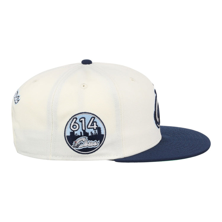 The Ebbets Field Columbus Clippers MiLB Snapback Ballcap is cream-colored with a navy bill and a circular side patch showing 