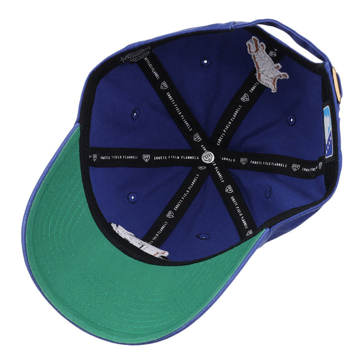 A look inside the blue Durham Bulls MiLB Dad Ballcap by Ebbets Field, featuring a green brim, black interior taping with white text and logos, metal eyelets, and an inner horse logo patch.