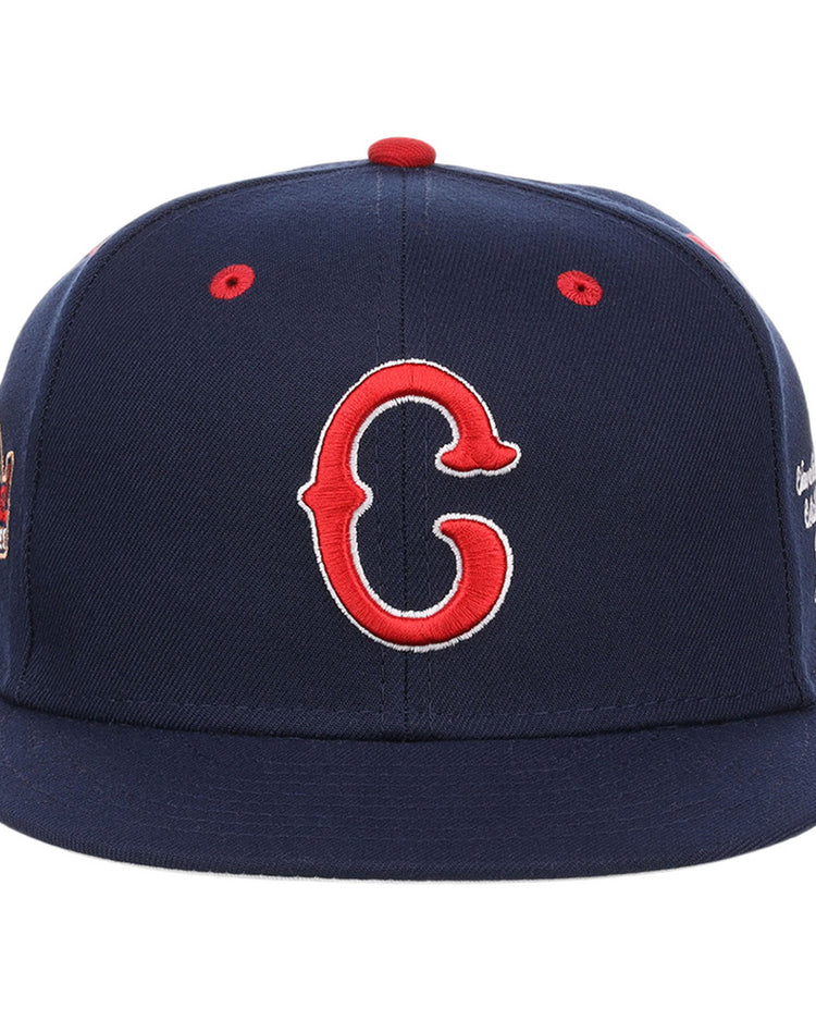 The Ebbets Field Cleveland Buckeyes NLB Varsity Fitted Ballcap features a navy base, red eyelets, a slightly curved brim, and an embroidered red and white 