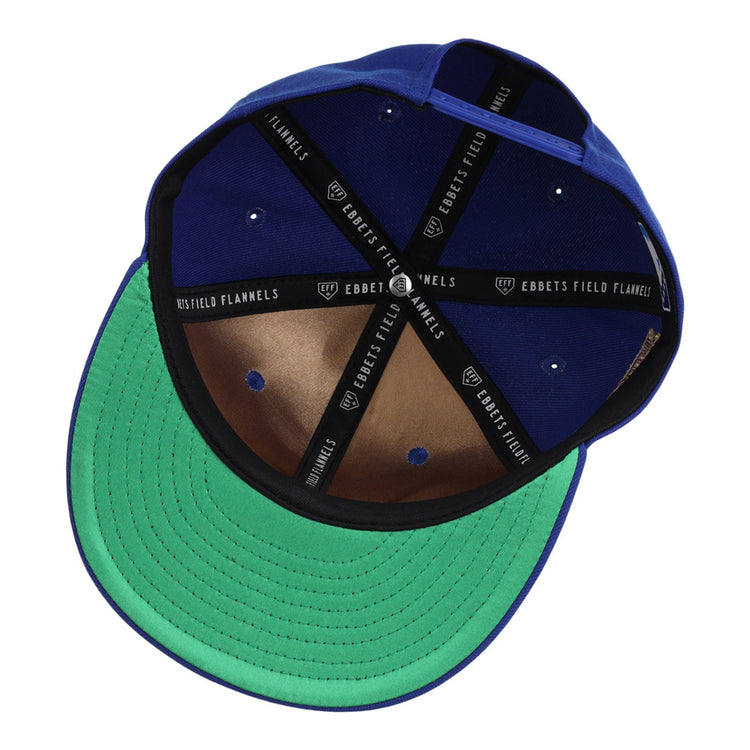The Ebbets Field Durham Bulls MiLB Snapback Ballcap is shown upside down, revealing its green underside brim, brown leather inner panel, black sweatband, and interior taping labeled EBBETS FIELD FLANNELS.
