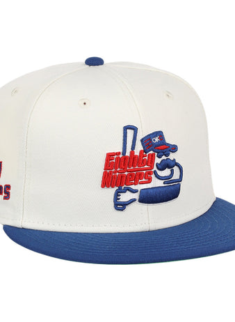 The Ebbets Field Oklahoma City 89Ers MiLB Logo Wordmark Snapback Ballcap features a white crown, blue brim, an embroidered cartoon mascot with 