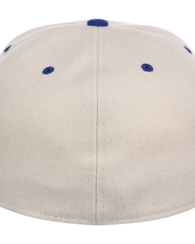 The Ebbets Field Brooklyn Royal Giants NLB Ballpark Fitted Ballcap is a beige cap seen from the back, with blue eyelets and a blue top button.