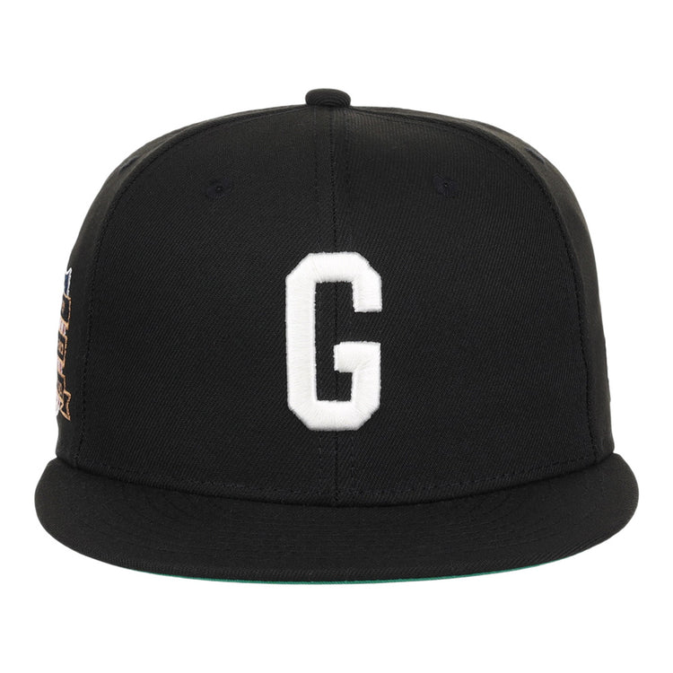 The Ebbets Field Homestead Grays NLB Tc Fitted Ballcap is a black cap with a flat brim, featuring a large white embroidered letter G on the front and minimal visible detailing.