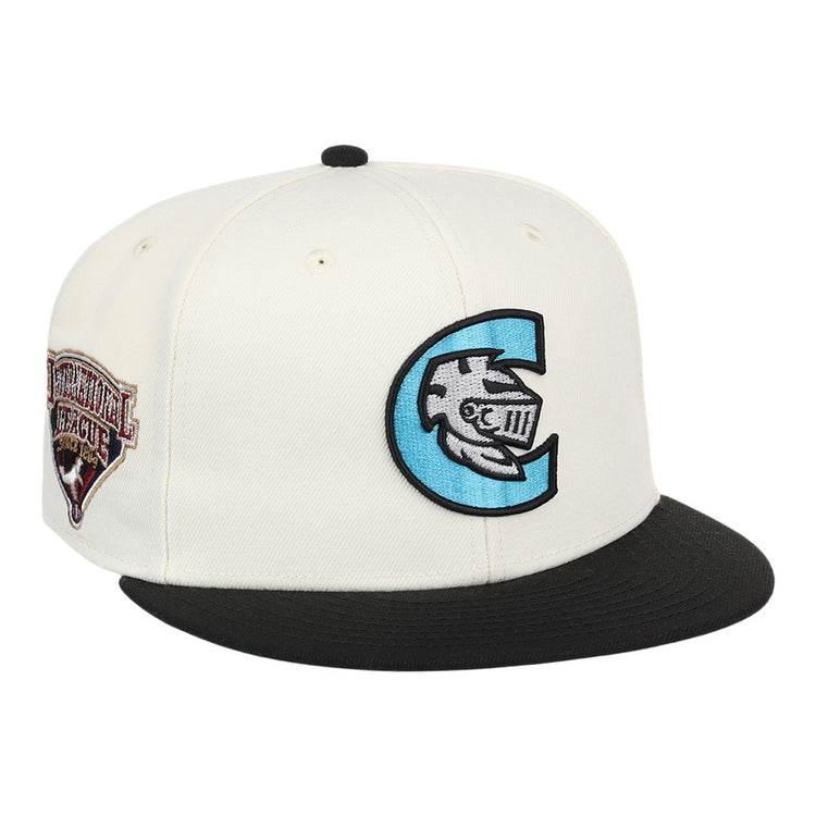 The Ebbets Field Charlotte Knights MiLB Snapback Ballcap is a white cap with a black brim, a large blue and black C logo with a fish and Roman numerals on the front, plus a brown Continental League patch on the side.