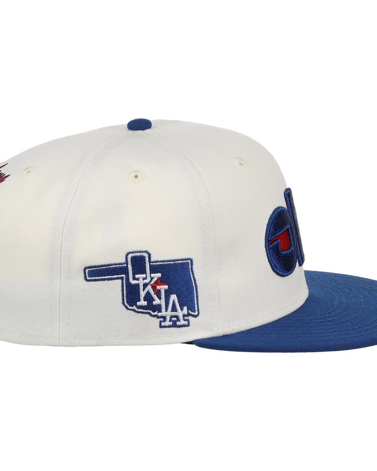 The Ebbets Field Oklahoma City Dodgers MiLB Snapback Ballcap is a white cap with a blue brim, side embroidery of Oklahoma with 
