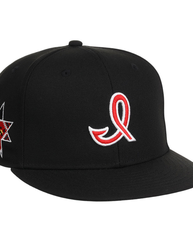 The Ebbets Field Indianapolis Indians MiLB Snapback Ballcap is a black hat with a red ribbon embroidered on the front and a multicolored star crowned design on the left side.
