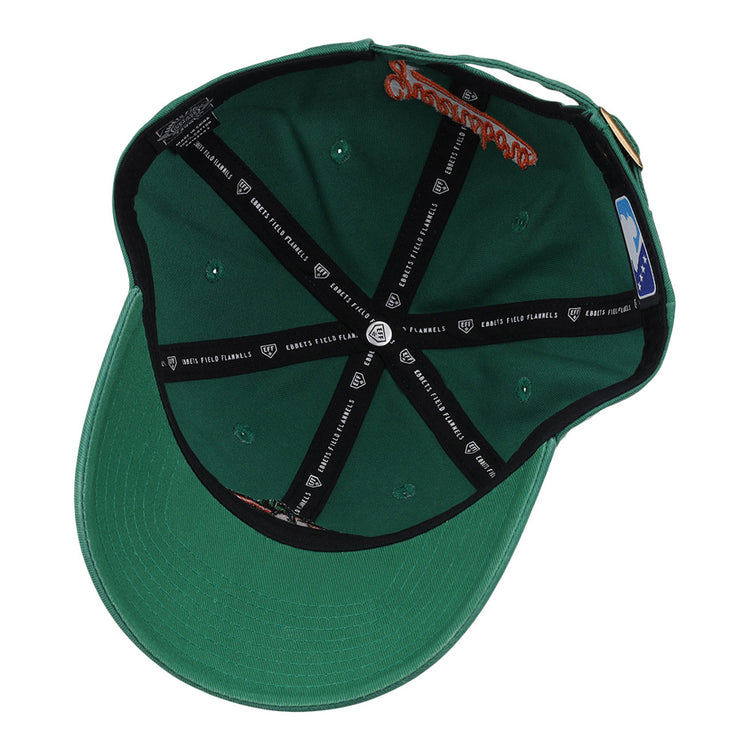 This image shows the inside of the Greensboro Grasshoppers MiLB Dad Ballcap by Ebbets Field, featuring black branded taping on the panels, a sticker on the inner sweatband, a size label on the side, and a green visor.