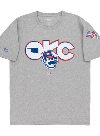 The Ebbets Field Oklahoma City 89Ers MiLB Fashion Cotton Short Sleeve Tee is a heather gray T-shirt with a large logo and cartoon character on the chest, plus 405 patches and other symbols on the sleeves.
