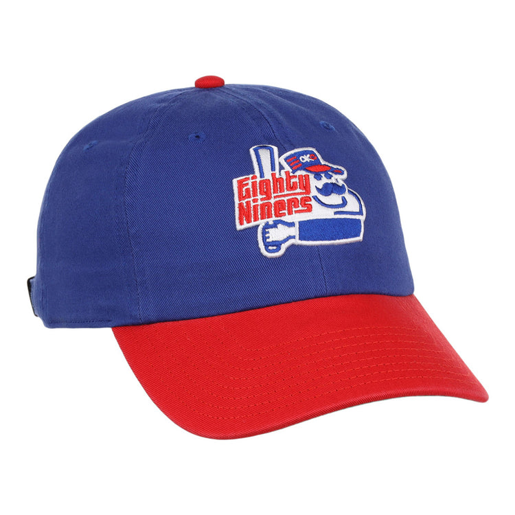 The Ebbets Field Oklahoma City 89Ers MiLB Logo Dad Ballcap is blue with a red brim, featuring an embroidered cartoon character holding a bat and “Eighty Niners” text on the front.