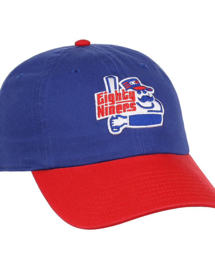 The Ebbets Field Oklahoma City 89Ers MiLB Logo Dad Ballcap is blue with a red brim, featuring an embroidered cartoon character holding a bat and “Eighty Niners” text on the front.