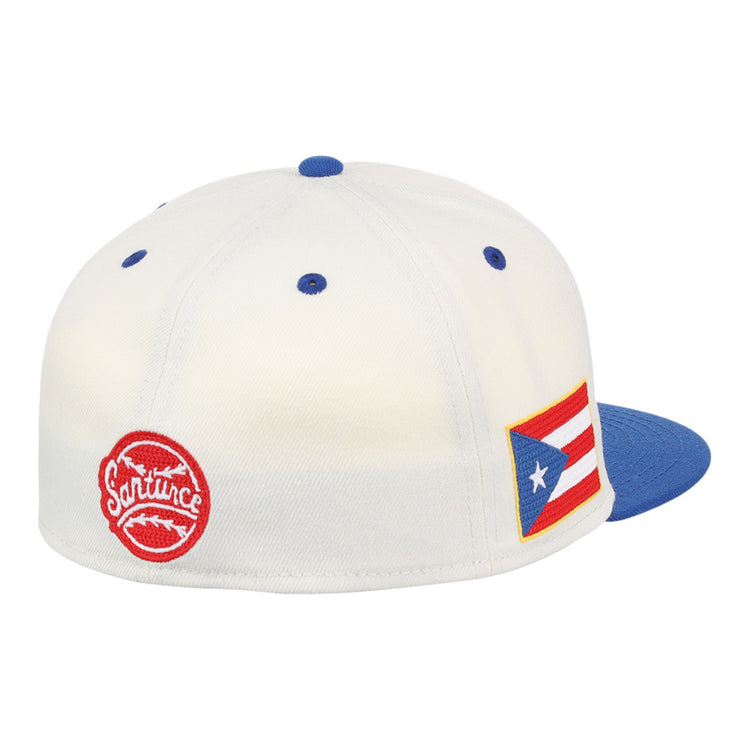 The Ebbets Field Santurce Cangrejeros Chainstitch Fitted Ballcap is white with a blue brim, a red circular Santurce logo, and a Puerto Rican flag patch on the side.