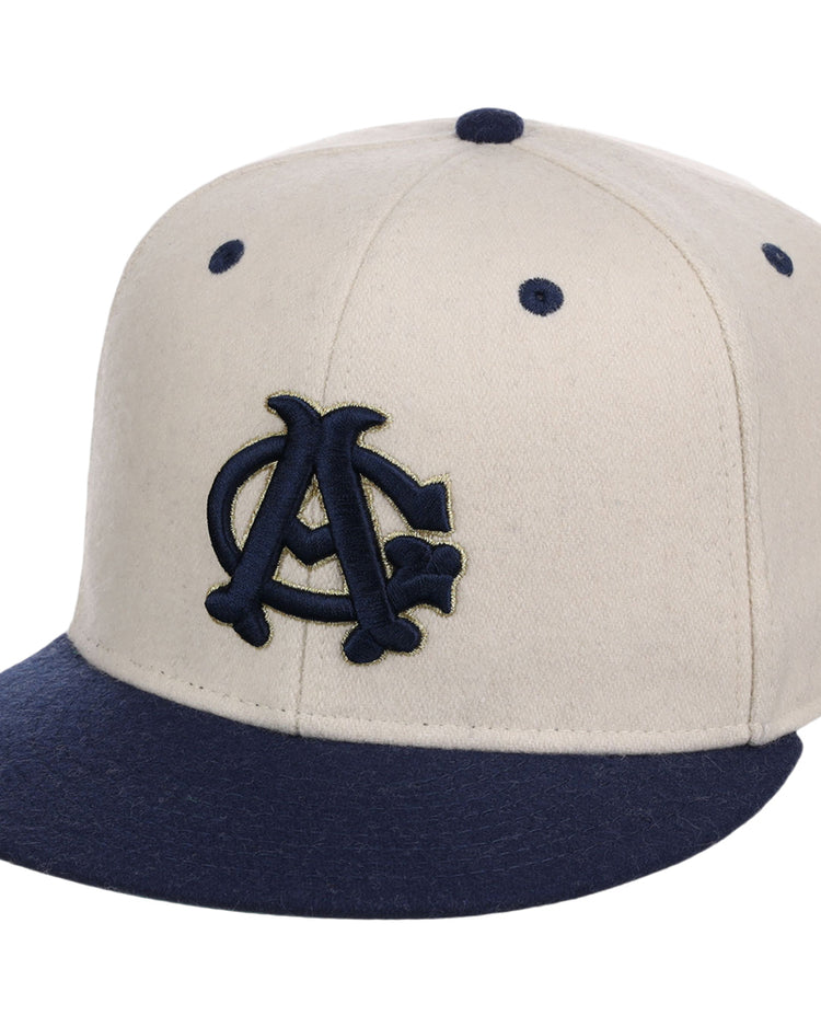 The Ebbets Field Chicago American Giants NLB Ballpark Fitted Ballcap features a cream color with a navy brim and embroidered navy and gold interlocking AC logo, plus ventilation holes on top.