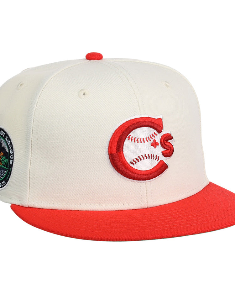 The Vancouver Canadians MiLB Snapback Ballcap by Ebbets Field is a cream cap with a red brim, featuring a red and white C logo with baseball stitching on the front and a circular patch with trees and text on the side.