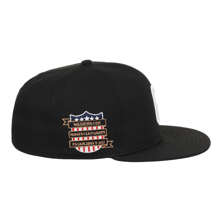 The Ebbets Field Homestead Grays NLB Tc Fitted Ballcap is a black, flat-brim cap with side embroidered patches—a shield with stars and stripes, plus banners reading Washington, Homestead Grays, and Established 1912.