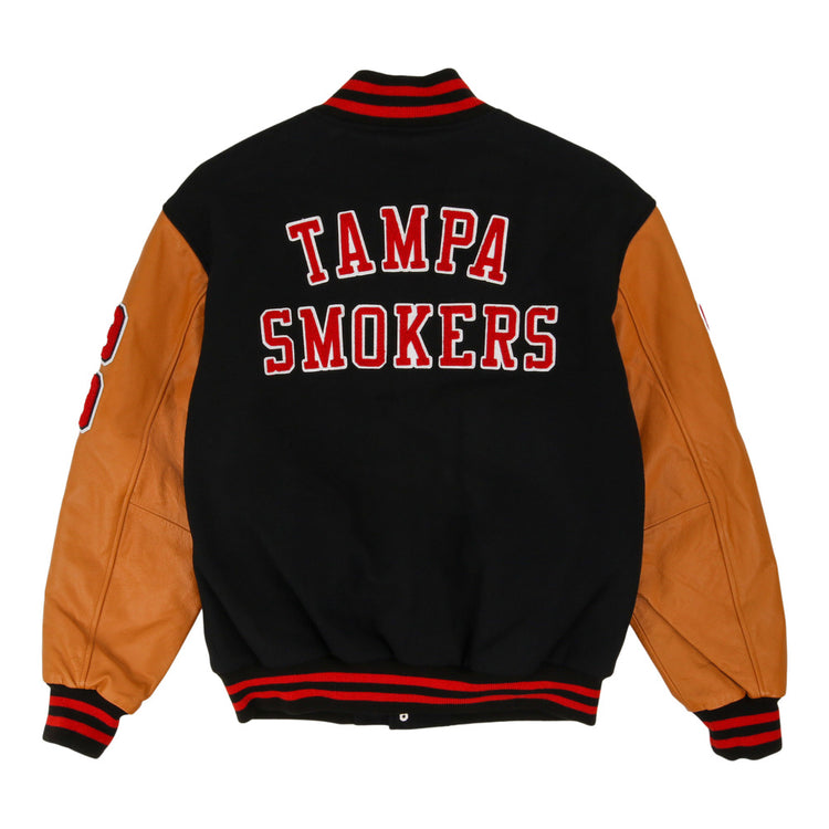 The Ebbets Field Tampa Smokers MiLB Dna Varsity Jacket features a black body, tan leather sleeves, red and white striped cuffs and collar, and 