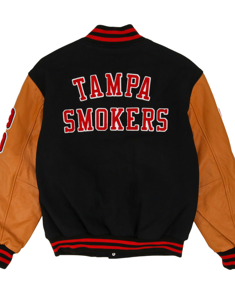 The Ebbets Field Tampa Smokers MiLB Dna Varsity Jacket features a black body, tan leather sleeves, red and white striped cuffs and collar, and 