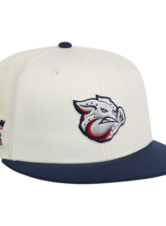 The Lehigh Valley Ironpigs MiLB Snapback Ballcap by Ebbets Field features a cream crown, navy brim, stylized pig logo on the front, and Bacon USA text with an American flag graphic on the side.