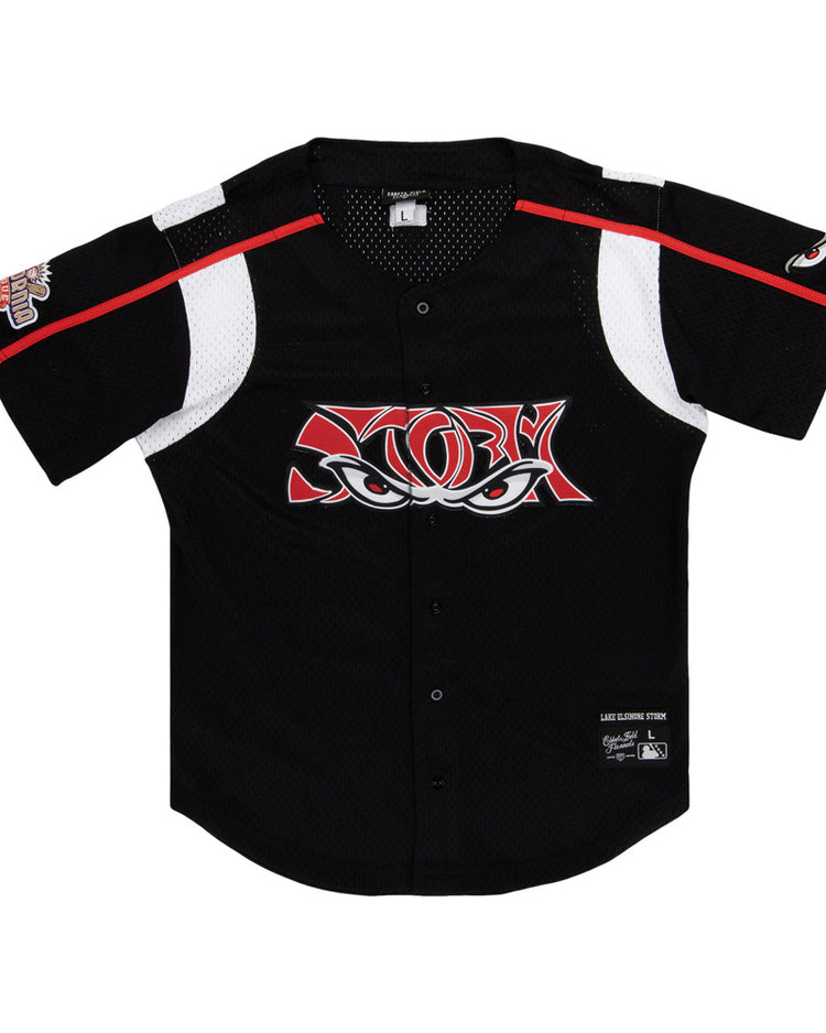 The Ebbets Field Lake Elsinore Storm MiLB Button Down Jersey is a black short-sleeve baseball jersey with white and red accents, mesh panels, a stylized eyes logo on the chest, and patches on the left sleeve and lower right front.