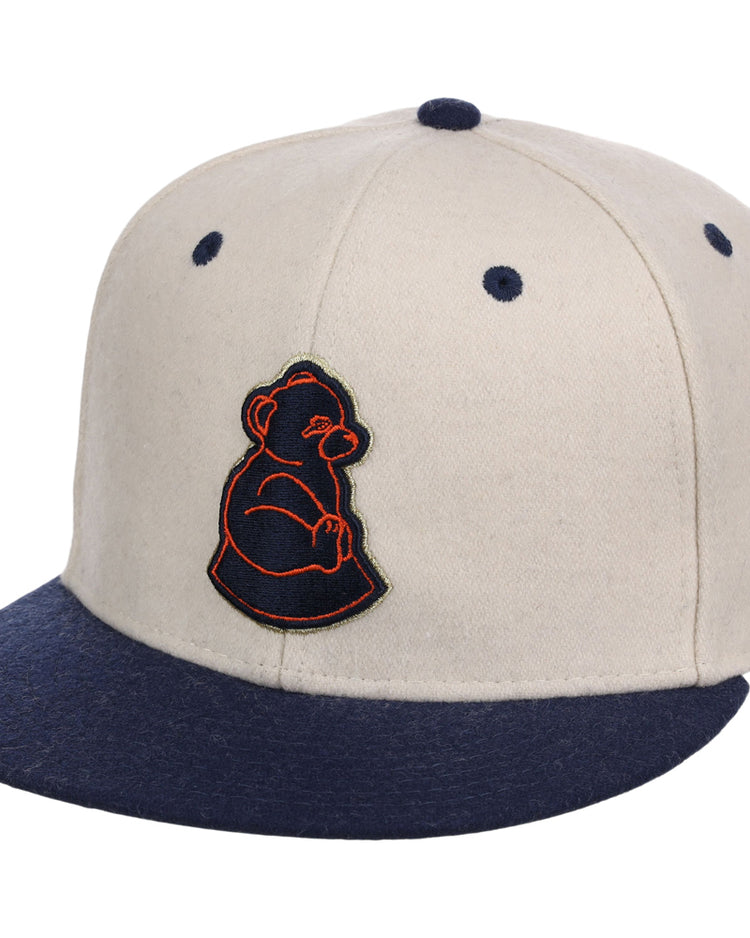 The Ebbets Field San Francisco Sea Lions NLB Ballpark Fitted Ballcap is beige with a navy brim and button, featuring a navy bear cub logo outlined in orange on the front.