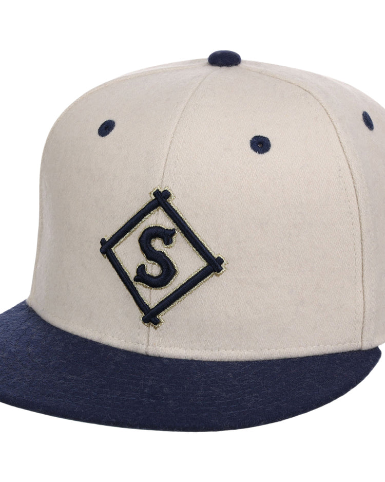 The Ebbets Field Seattle Steelheads NLB Ballpark Fitted Ballcap is beige with a navy brim and button, and displays a navy 
