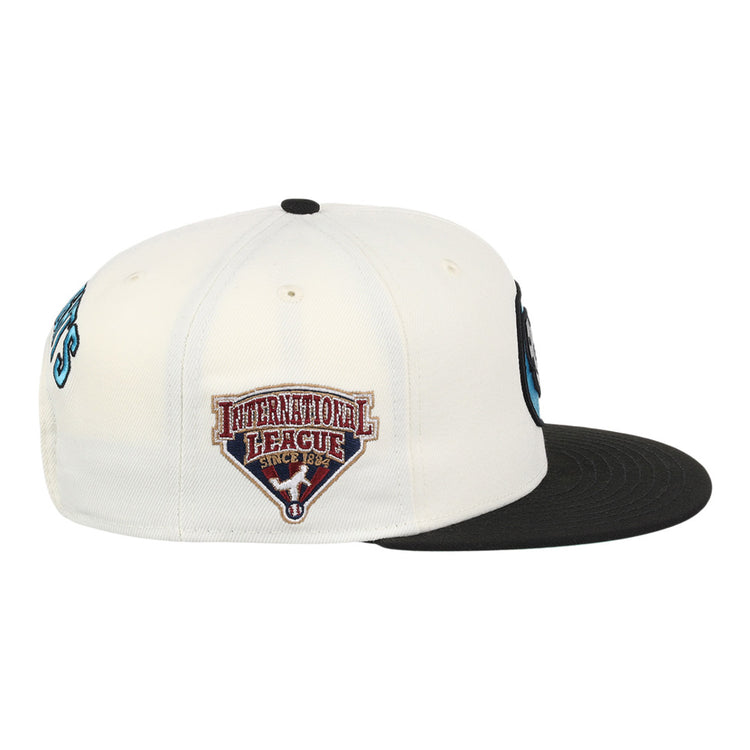 The Ebbets Field Charlotte Knights MiLB Snapback Ballcap is a black and white cap, shown from the side, featuring an International League Since 1884 patch with a red and white shield on the side panel.