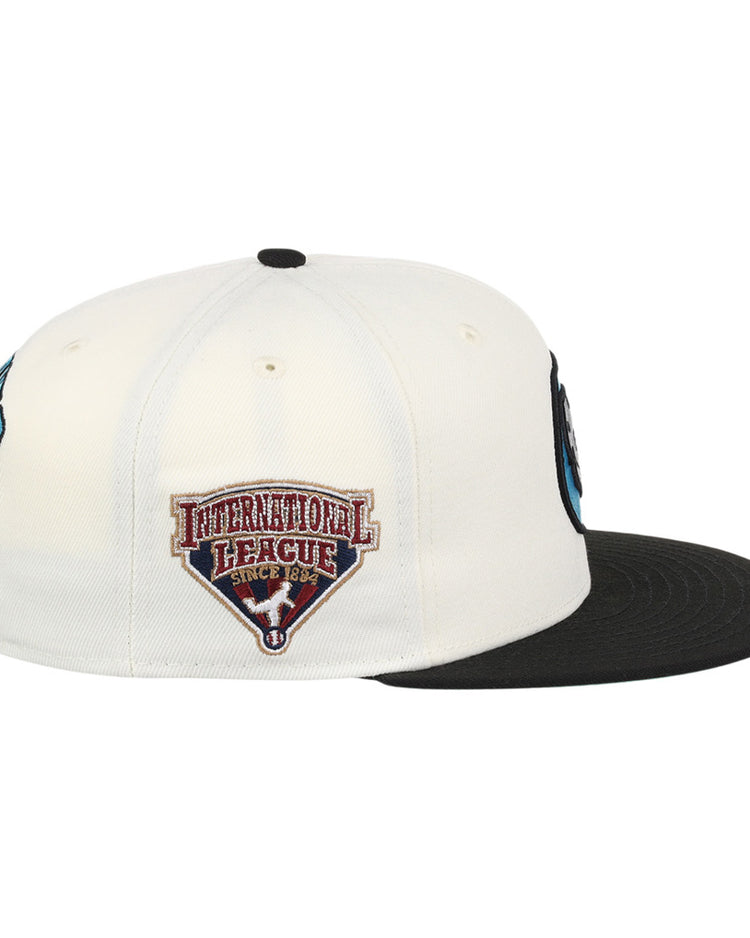The Ebbets Field Charlotte Knights MiLB Snapback Ballcap is a black and white cap, shown from the side, featuring an International League Since 1884 patch with a red and white shield on the side panel.