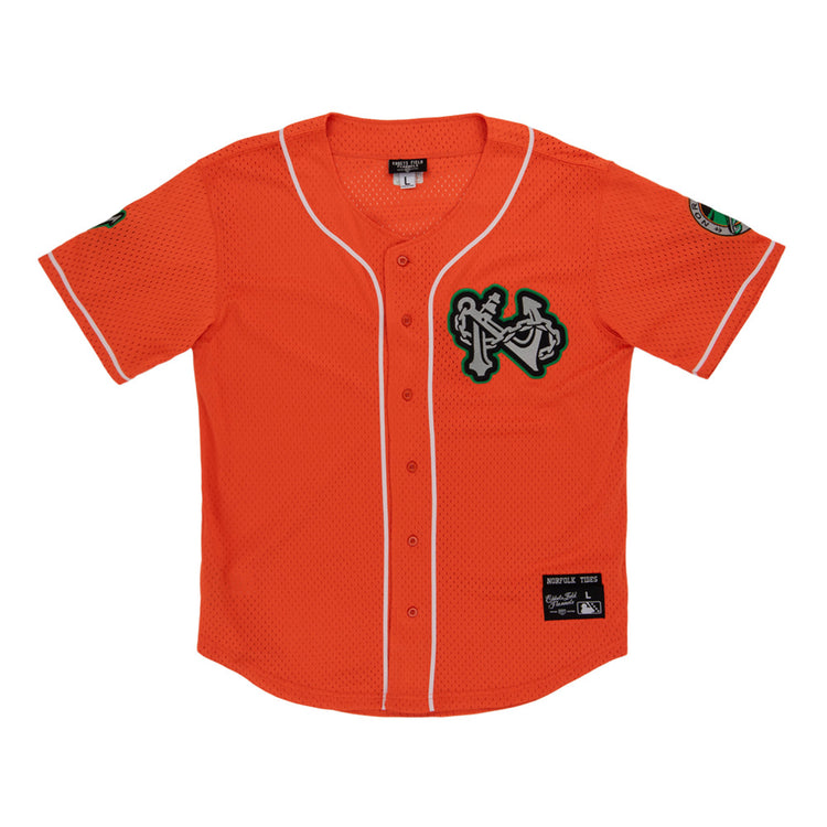 The Ebbets Field Norfolk Tides MiLB Button Down Jersey features orange fabric with white trim, a green-and-white chest logo patch, sleeve patches, a button front, and a black manufacturer's label above the hem.