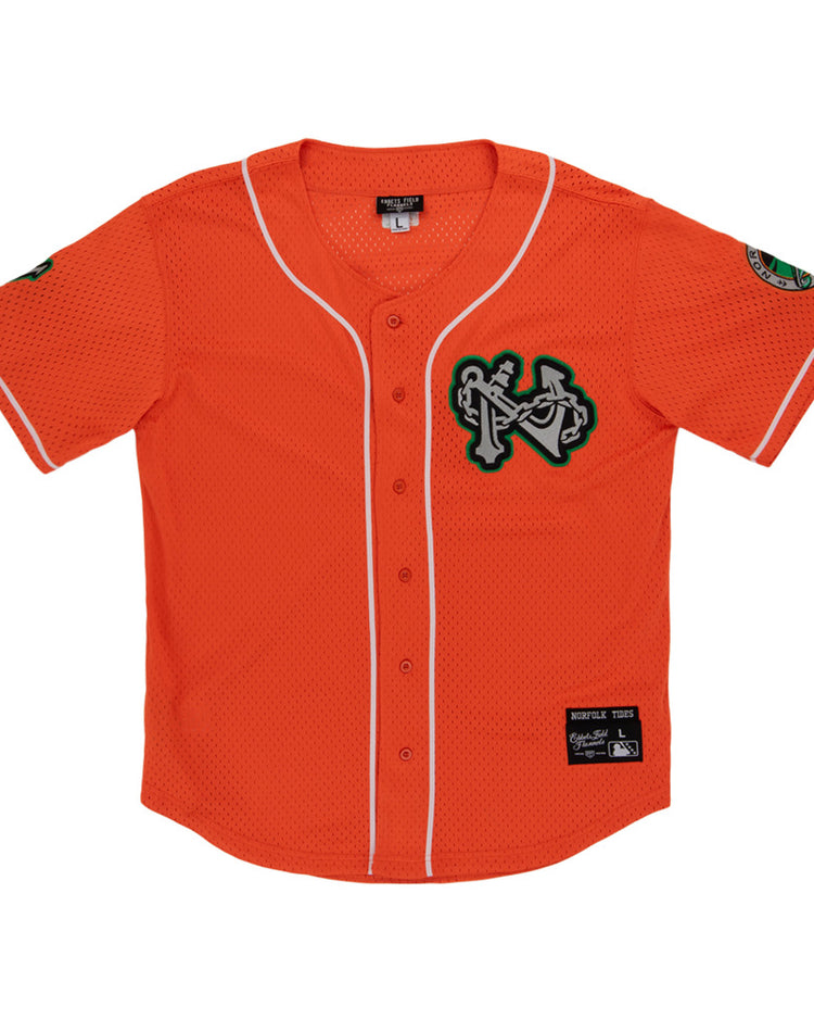 The Ebbets Field Norfolk Tides MiLB Button Down Jersey features orange fabric with white trim, a green-and-white chest logo patch, sleeve patches, a button front, and a black manufacturer's label above the hem.
