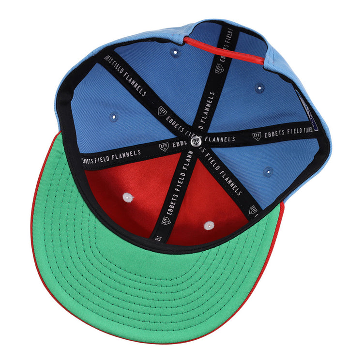 An upside-down Ebbets Field Corpus Christi Hooks MiLB Snapback Ballcap shows a blue crown, red inner front panel, green brim underside, black sweatband, and black EBBETS FIELD FLANNELS branded taping.