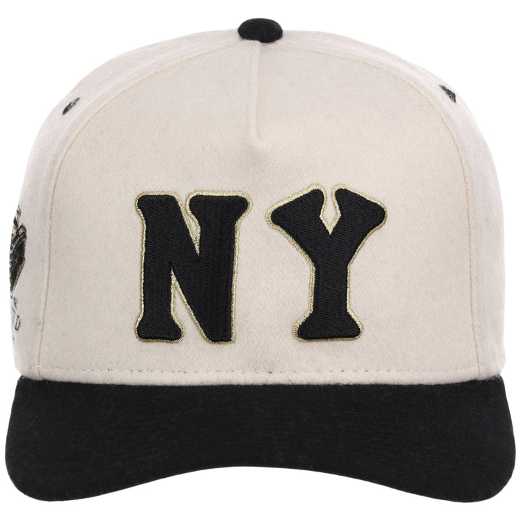 The Ebbets Field New York Black Yankees NLB Ballpark A-Frame Ballcap is beige with a black brim and features large black “NY” letters outlined in gold on the front.
