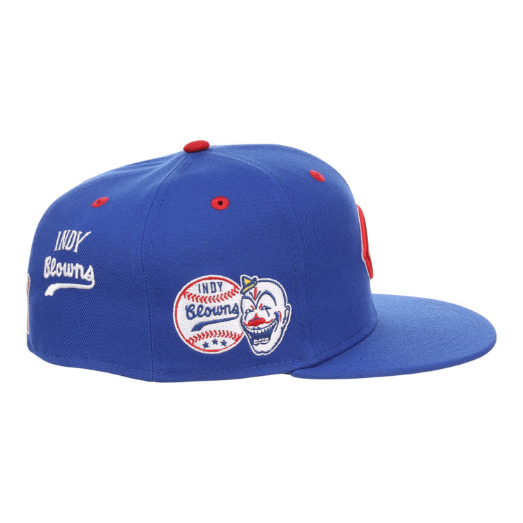 The Ebbets Field Indianapolis Clowns NLB Varsity Fitted Ballcap is a blue cap with a red top button, embroidered Indy Browns baseball graphics, a smiling clown face on the side, and white 