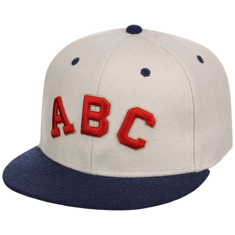 The Ebbets Field Atlanta Black Crackers NLB Ballpark Fitted Ballcap is beige with a dark blue brim and top button, featuring bold red “ABC” letters on the front.