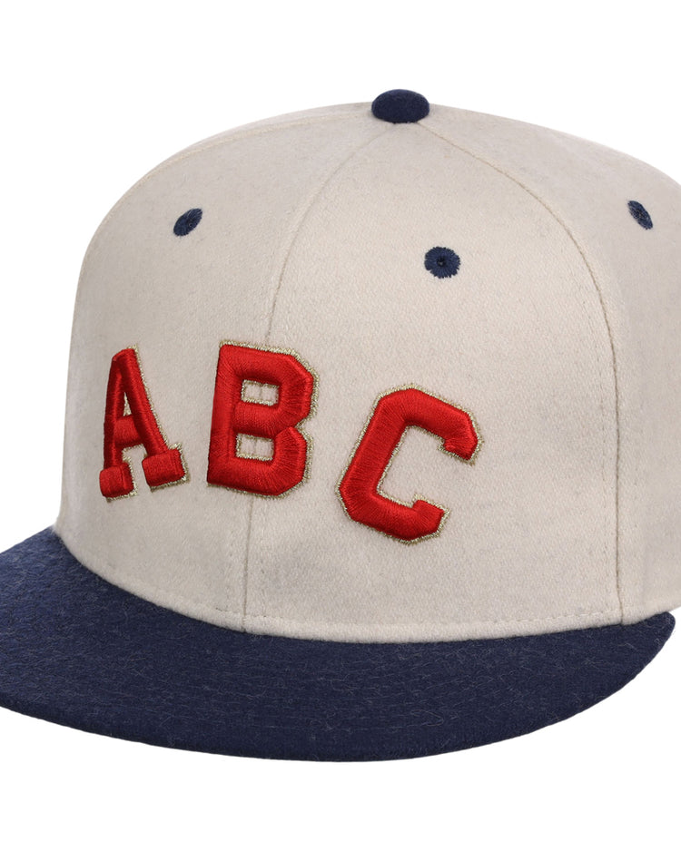 The Ebbets Field Atlanta Black Crackers NLB Ballpark Fitted Ballcap is beige with a dark blue brim and top button, featuring bold red “ABC” letters on the front.