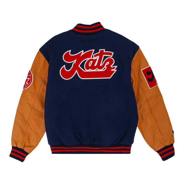 The Ebbets Field Kansas City Katz Dna Varsity Jacket has a navy body, tan sleeves, red accents, a large red and white Katz patch on the back, and round plus square patches on the sleeves.