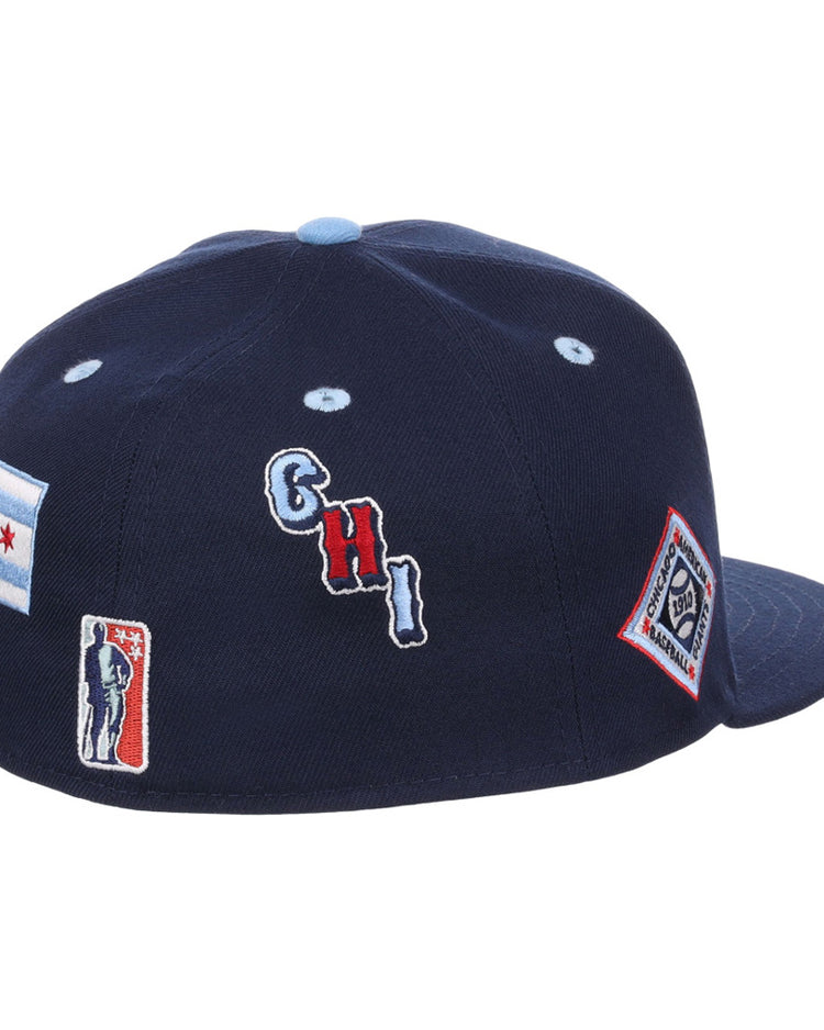 The Ebbets Field Chicago American Giants NLB Varsity Fitted Ballcap is a navy blue cap with embroidered patches—a Chicago flag, CHI letters, baseball player silhouette, and diamond-shaped logo—on the back and side.