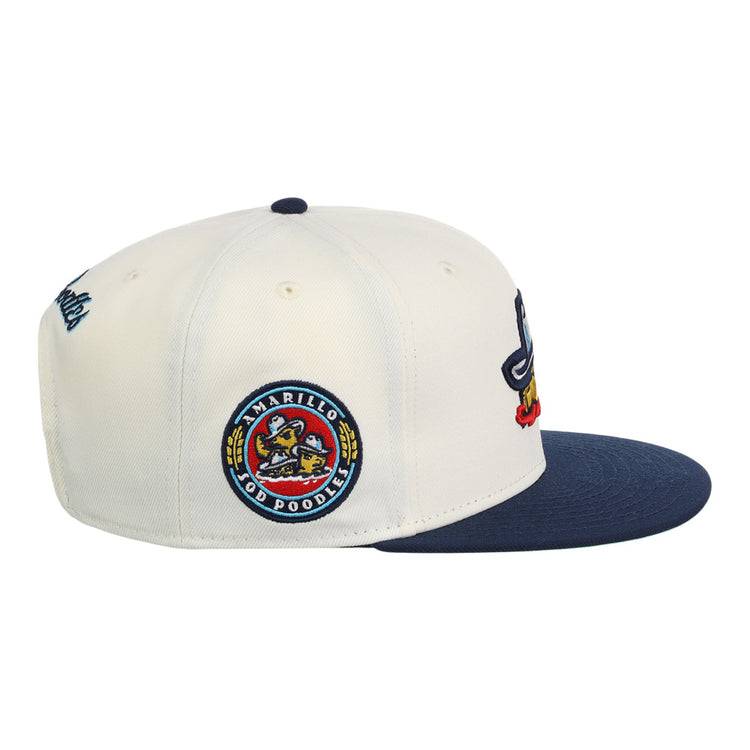 The Ebbets Field Amarillo Sod Poodles MiLB Snapback Ballcap is white and navy with a round team logo patch on the side, a blue brim, and colorful embroidered designs on the front.